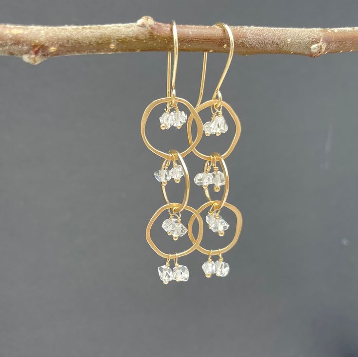 "14k Solid Gold Herkimer Diamond Dangle Earrings.  These playful solid gold dangle earrings have a waterfall of Herkimer Diamonds tumbling through three irregular shaped 14k gold hoops. Herkimer diamonds are double-terminated quartz crystals - they have a lovely sparkle that plays off the swiveling gold hoops and glint as they catch and reflect the light.  They are 14k solid gold and measure 2.25\" long by 0.5\" wide. They are handmade to order.  All designs come in a box ready for gifting." Yellow Gold Dangle Diamond Earrings For Anniversary, Hammered Yellow Gold Dangle Hoop Earrings, Yellow Gold Dangle Hoop Earrings With Hammered Texture, Gold Cluster Earrings With Ear Wire For Anniversary, Yellow Gold Hammered Dangle Hoop Earrings, Gold Dangle Cluster Earrings Fine Jewelry, Gold Briolette Diamond Earrings, 14k Gold Dangle Diamond Earrings With Diamond Cut, Yellow Gold Dangle Cluster Earrings For Anniversary