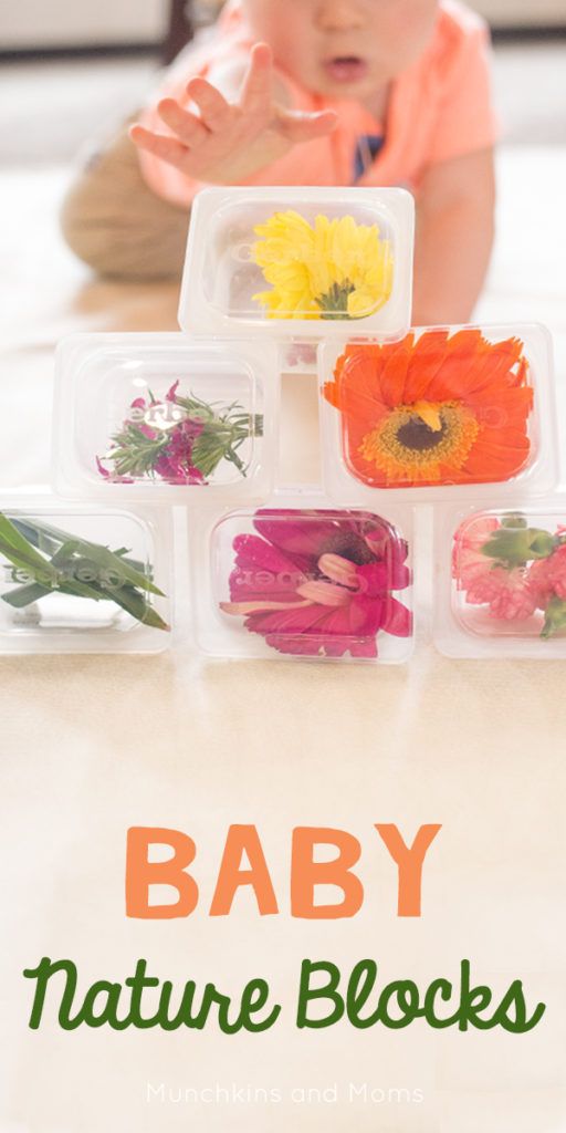 a baby playing with nature blocks on the floor in front of her mother's flowers