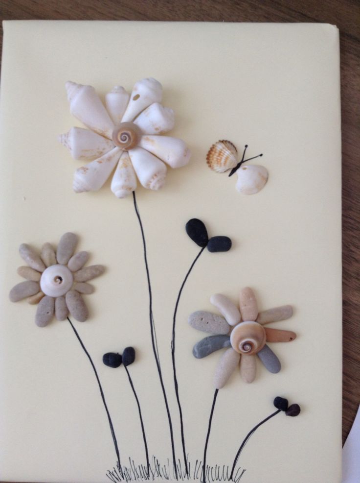 three flowers made out of seashells on a white board