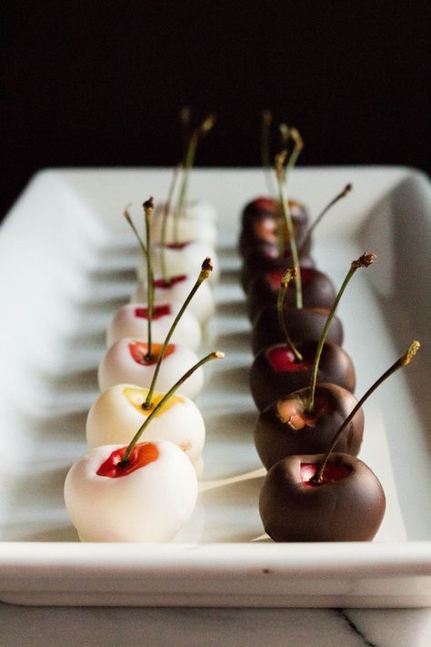 small appetizers are lined up on a white platter with cherry toppings