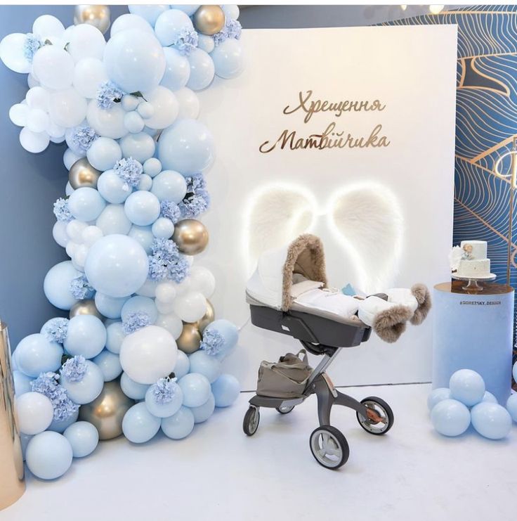 a baby stroller is next to a backdrop with balloons and an angel - shaped balloon