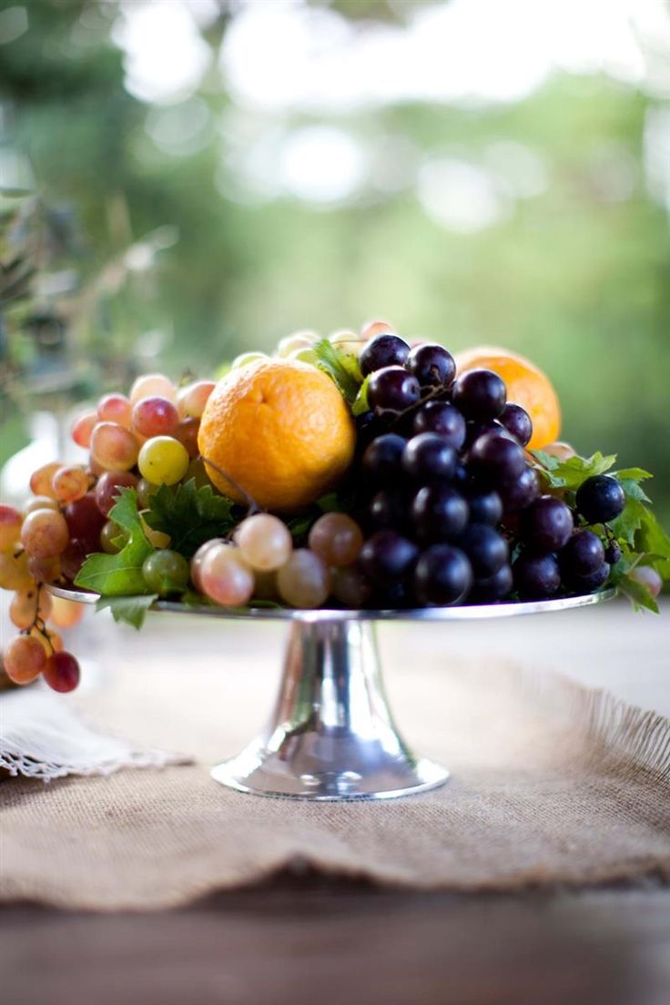 a plate with grapes, oranges and other fruit on it sitting on a table