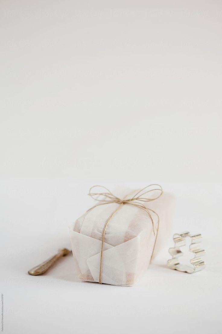 a white present box tied with twine and ribbon next to some cookies on a table