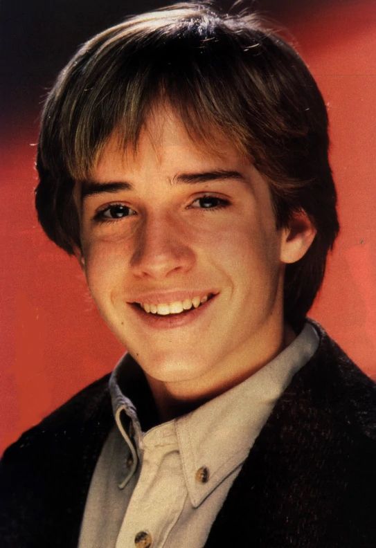 a young man smiling and wearing a black jacket