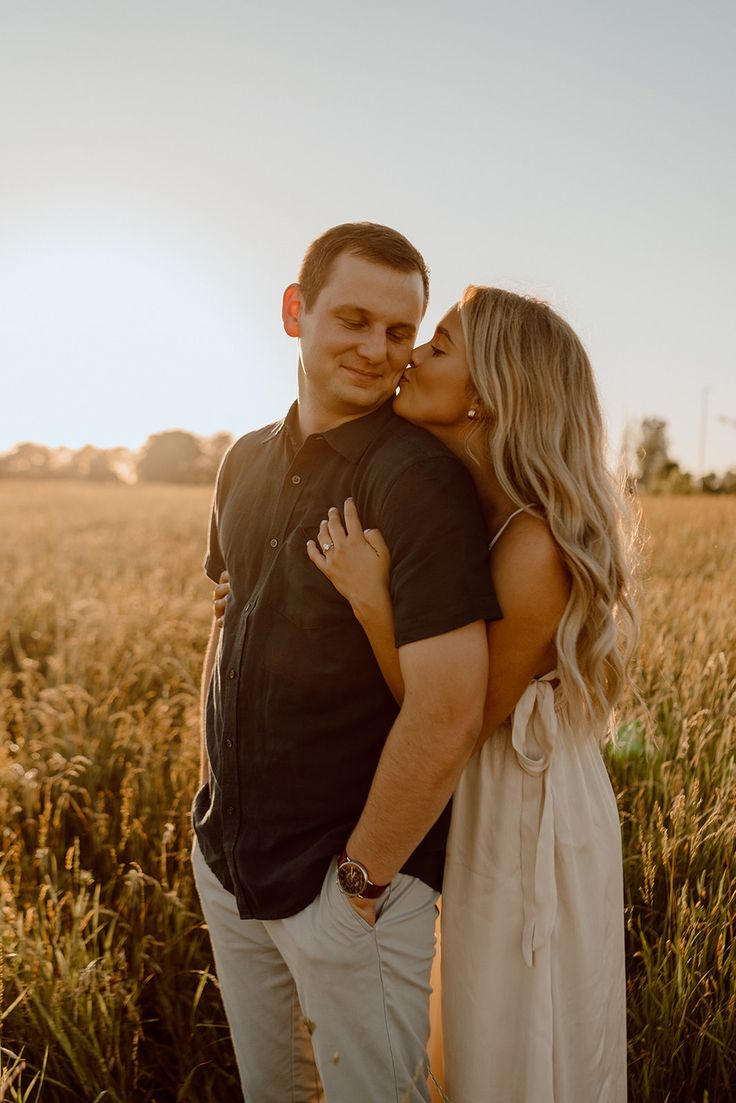 a man and woman are kissing in the middle of a wheat field with sun shining on them