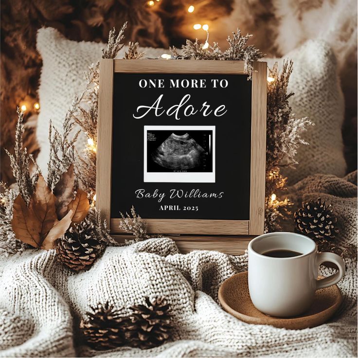 a coffee cup sitting on top of a table next to a sign that says, one more to adore