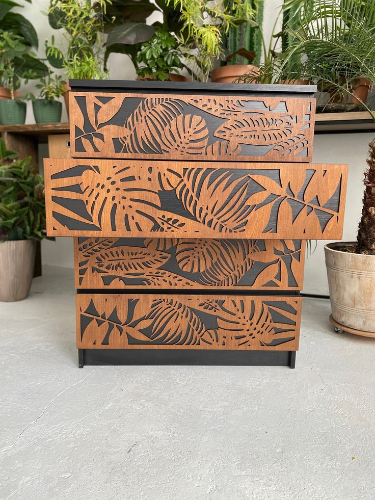 a wooden box sitting on top of a cement floor next to potted plants and trees