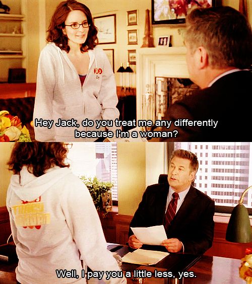 a woman is sitting at a desk talking to a man in a suit and tie