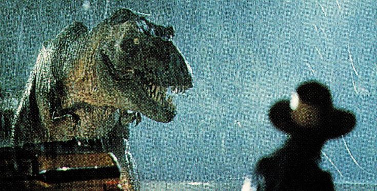 a person standing in the rain next to a dinosaur