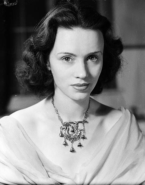 an old black and white photo of a woman in a dress with a necklace on her neck