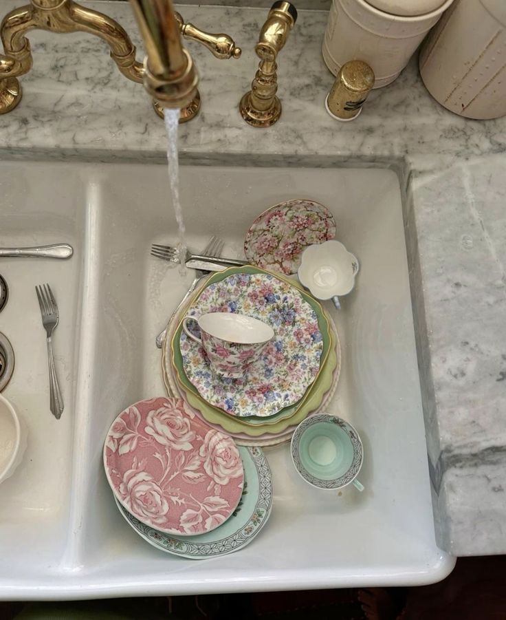 a sink filled with plates and cups next to a faucet