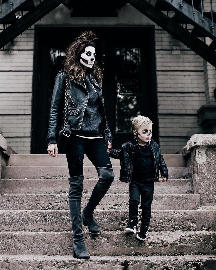 a woman and child are walking down the stairs in front of a house with skulls on their faces