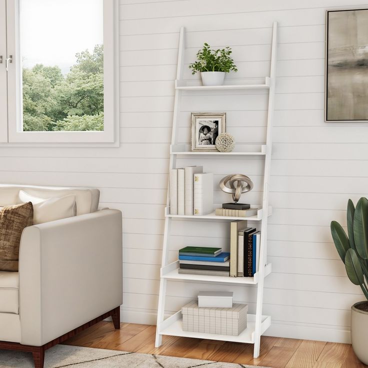 a living room with a white ladder book shelf next to a chair and potted plant