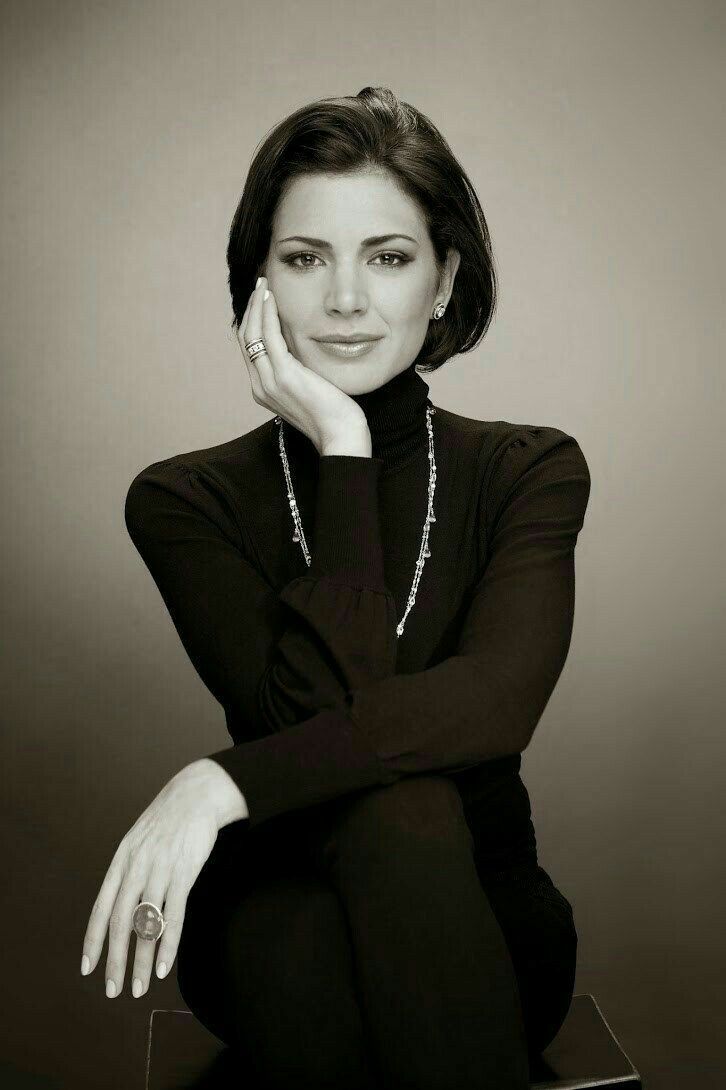 a black and white photo of a woman with her hand on her chin, posing for the camera