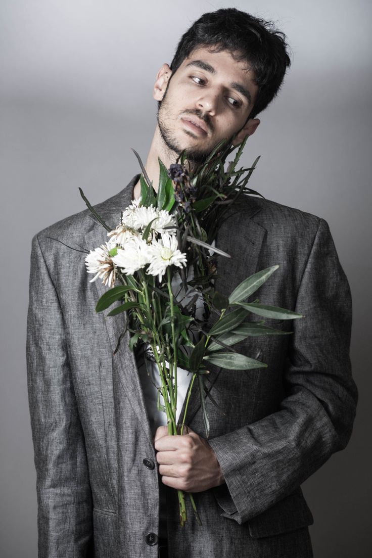 a man wearing a suit and holding flowers