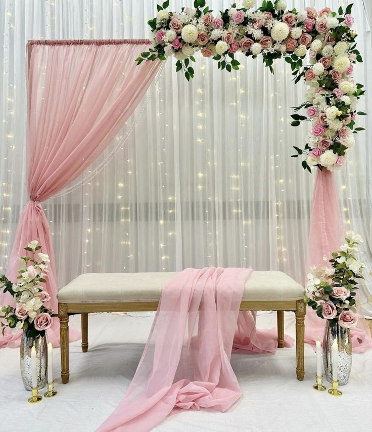 a white and pink wedding ceremony setup with flowers on the table, draping