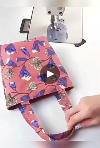 a person is using a sewing machine to sew a handbag on a table