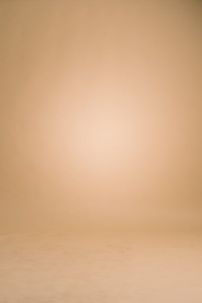 an orange and white vase sitting on top of a table next to a brown wall