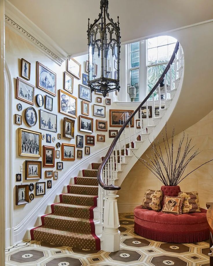 a staircase with pictures on the wall and a chandelier hanging from the ceiling