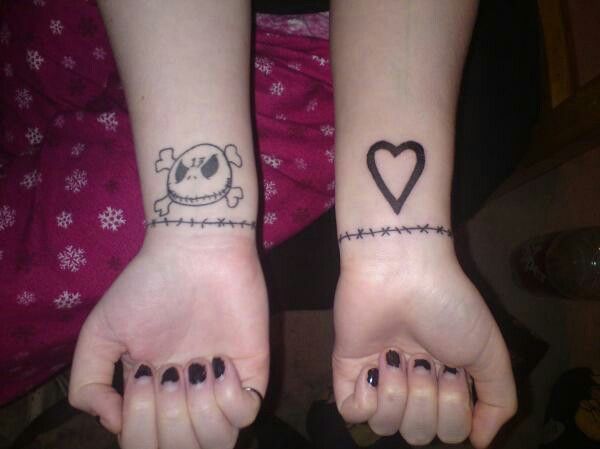 two girls with matching tattoos on their arms holding hands in the shape of heart and barbed wire