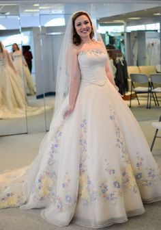 a woman standing in front of a mirror wearing a wedding dress