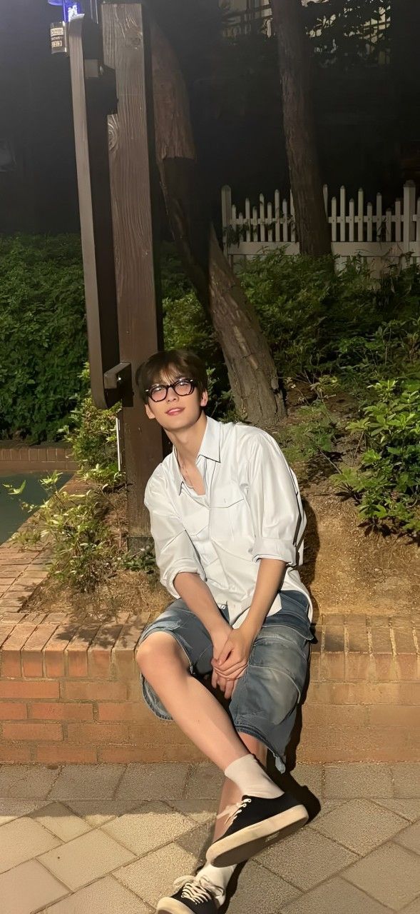 a young man sitting on top of a wooden bench