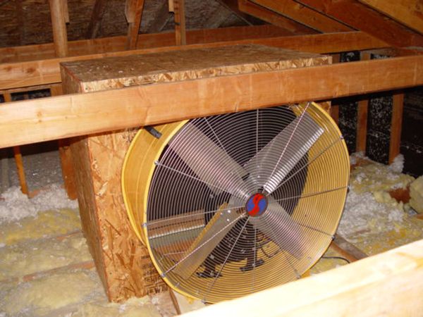 an attic fan in the corner of a room with insulation on the floor and walls