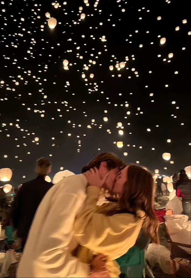 a man and woman kissing in front of floating lanterns