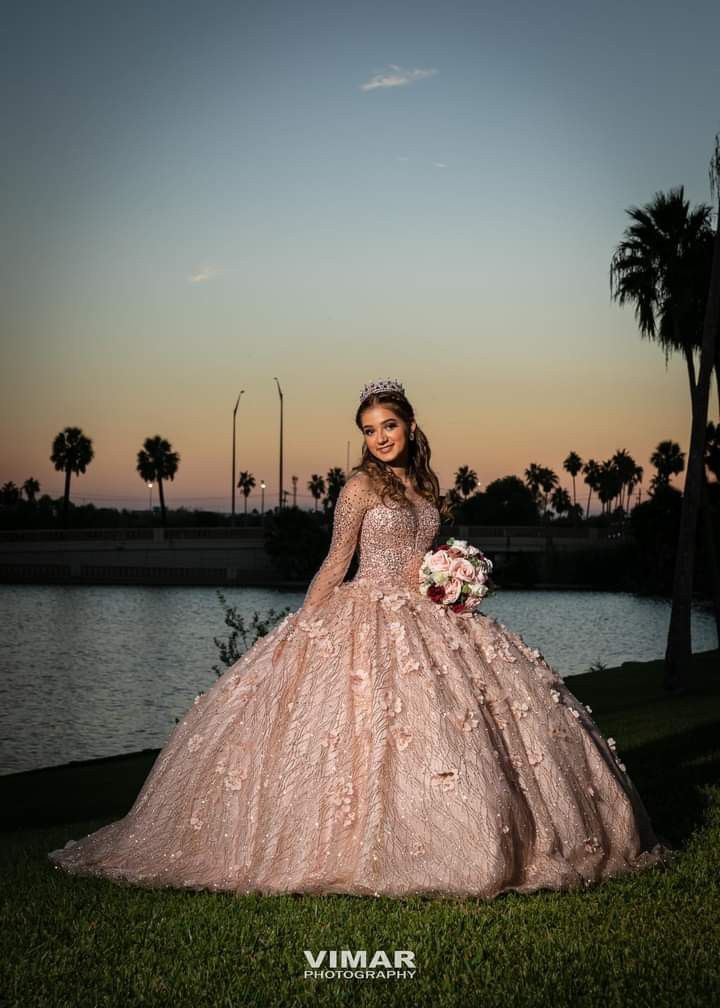 a woman in a wedding dress standing by the water at sunset with palm trees behind her