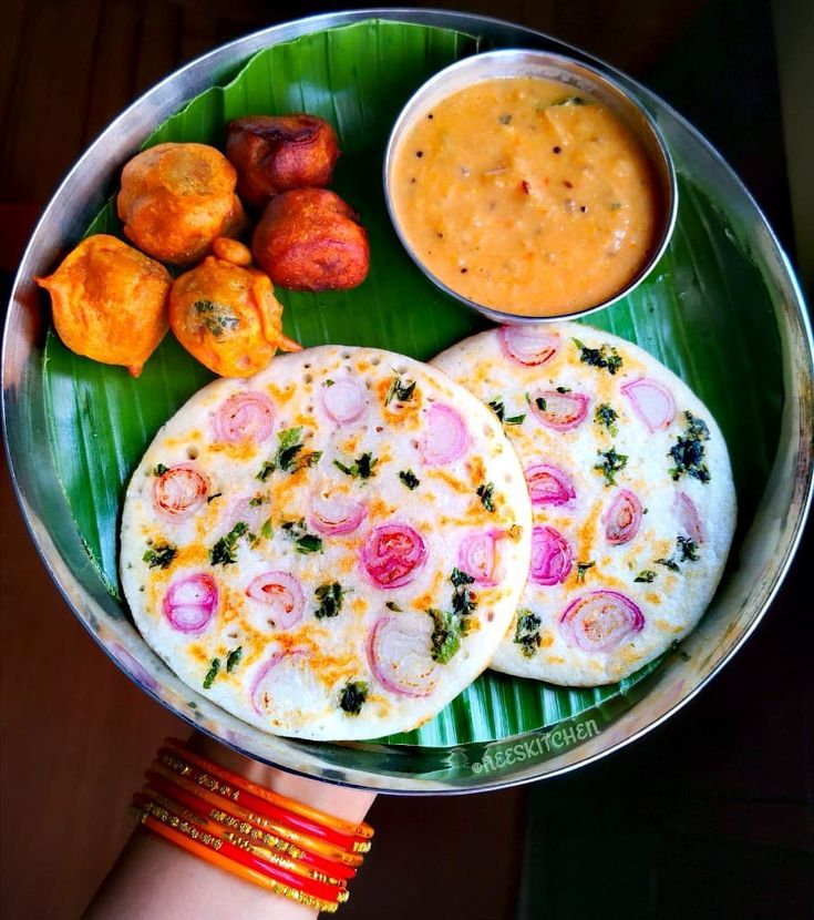 two flatbreads on a plate with dipping sauce and other foods in the background