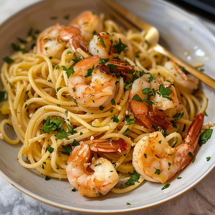 a plate of pasta with shrimp and parsley