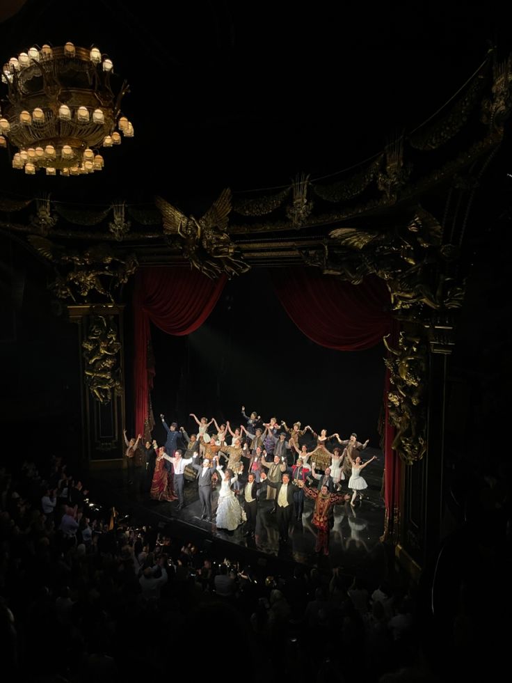 a group of people standing on top of a stage in front of a red curtain