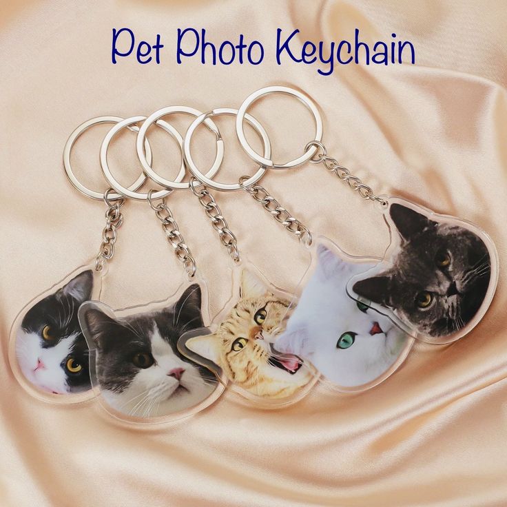 four keychains with pictures of cats on them, one has a cat's head