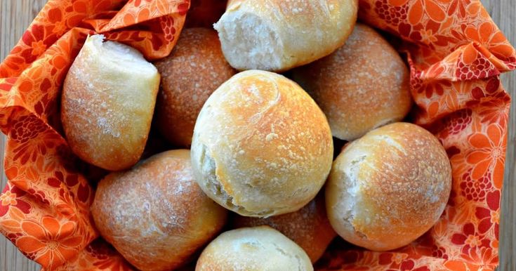 a bunch of bread rolls sitting in a basket on top of a table with an orange cloth