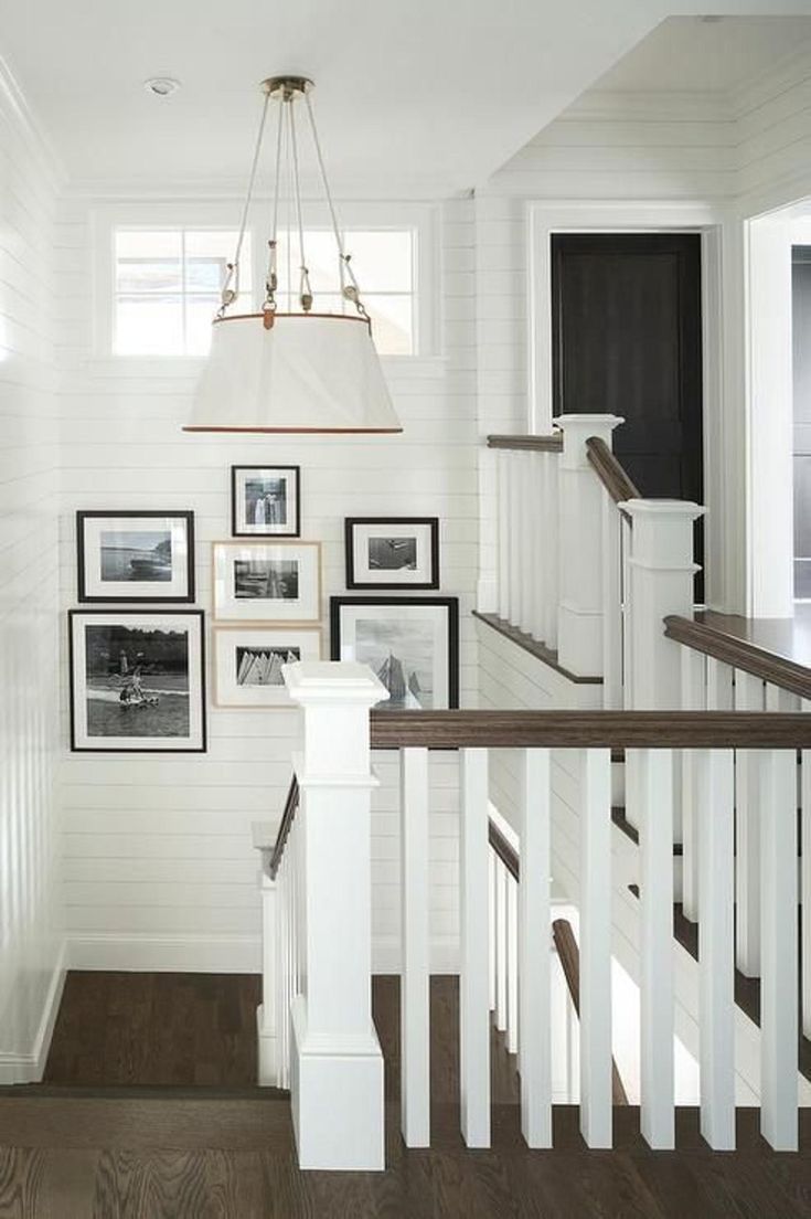 a white staircase with pictures on the wall and framed photos on the bannister