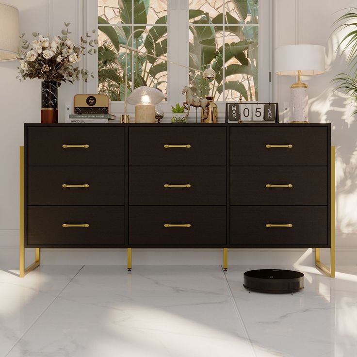 a black and gold dresser sitting in front of a window