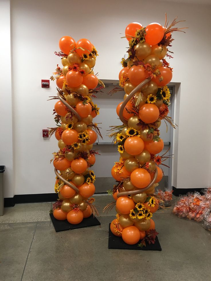 two tall orange and gold balloons with sunflowers on them in an office hallway