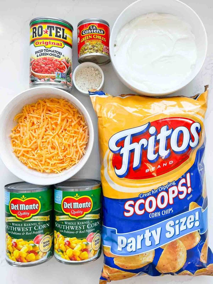 ingredients to make potato soup laid out on a white counter top, including cheese, sour cream and chips