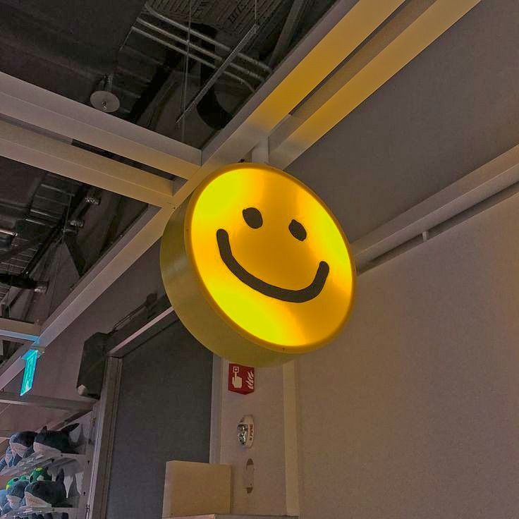 a yellow smiley face sign hanging from the ceiling