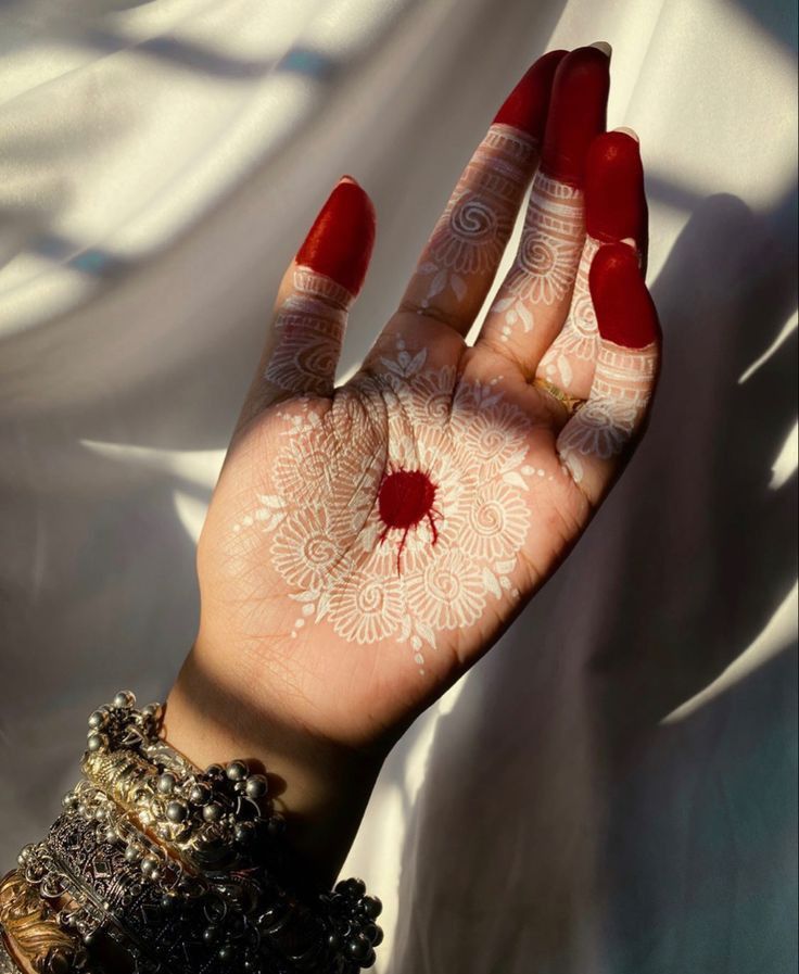 a woman's hand painted with white and red hendigns on it