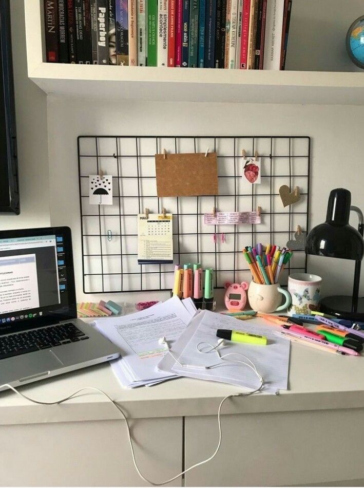 a laptop computer sitting on top of a desk next to a book shelf filled with books