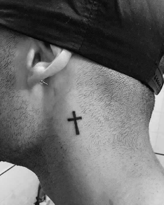 a man with a cross tattoo on his neck and behind his ear, looking down at the ground