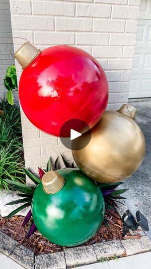 two large red and one green christmas ornaments sitting on top of each other in front of a white brick wall