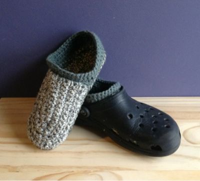 two crocheted clogs sitting on top of a wooden table next to a purple wall