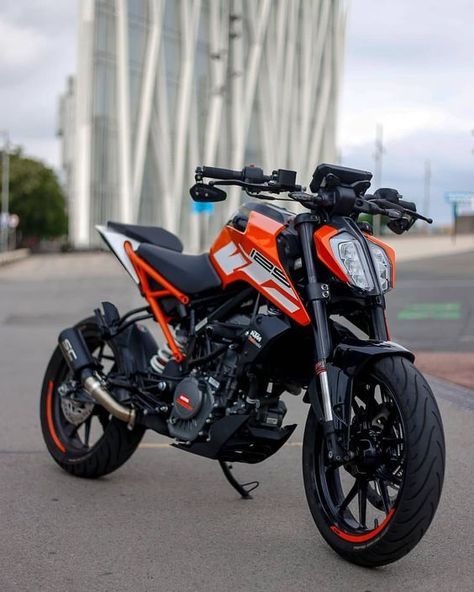 an orange and black motorcycle is parked on the side of the road in front of a building