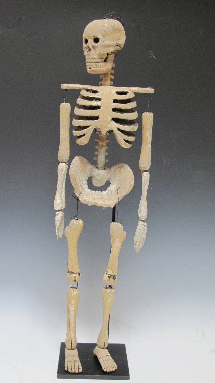 a wooden skeleton is standing on a black base