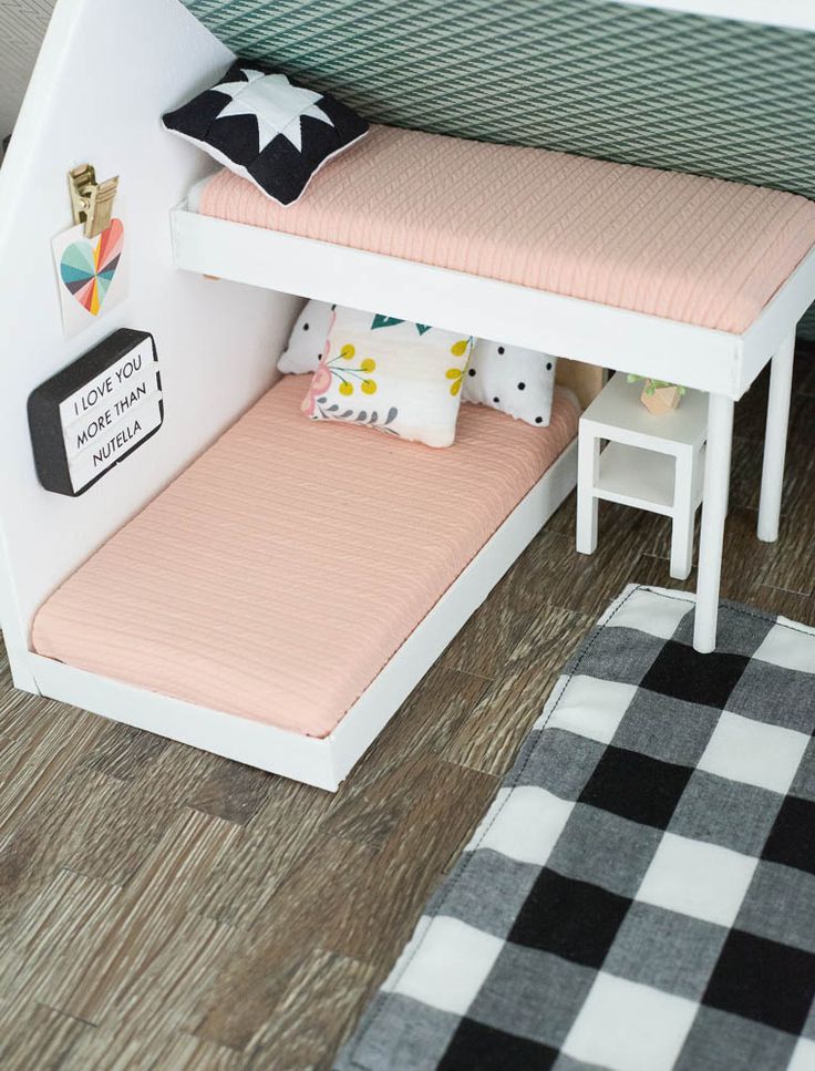 a dollhouse bed with a pink mattress underneath it