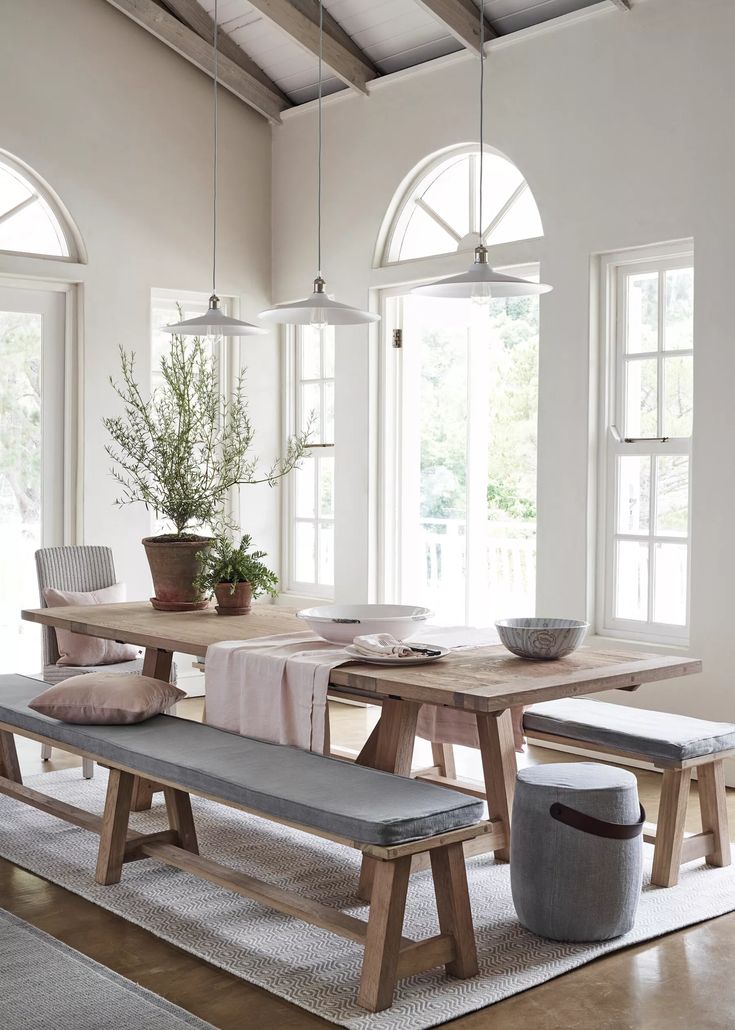 a dining room table with benches and potted plants on the table in front of it