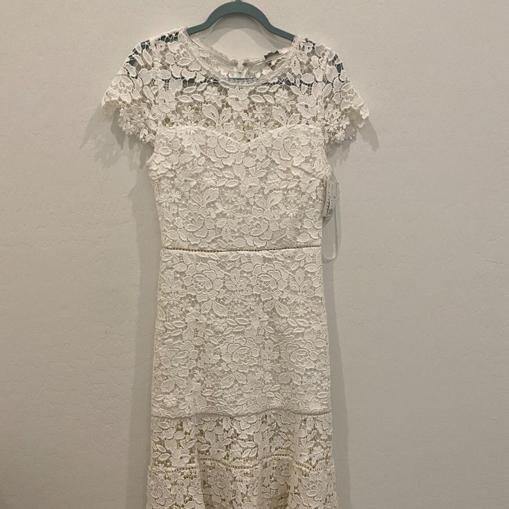 a white lace dress hanging on a hanger