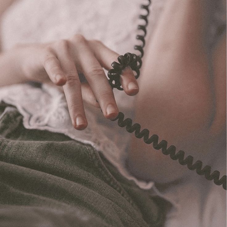 a woman is laying down on her stomach and talking on the phone with one hand